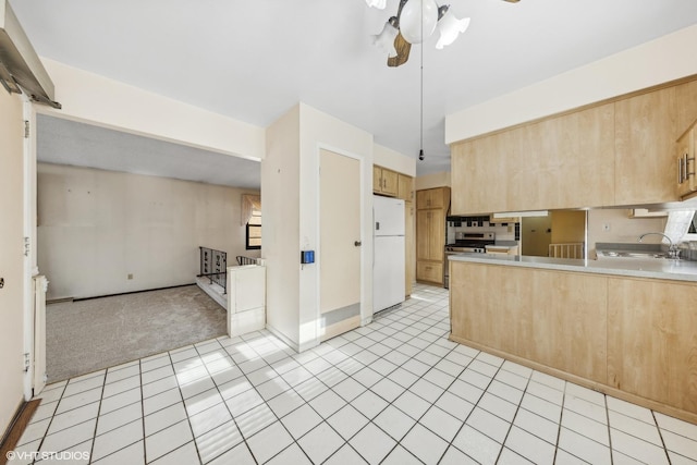 kitchen with stainless steel range, light brown cabinets, white refrigerator, light carpet, and ceiling fan