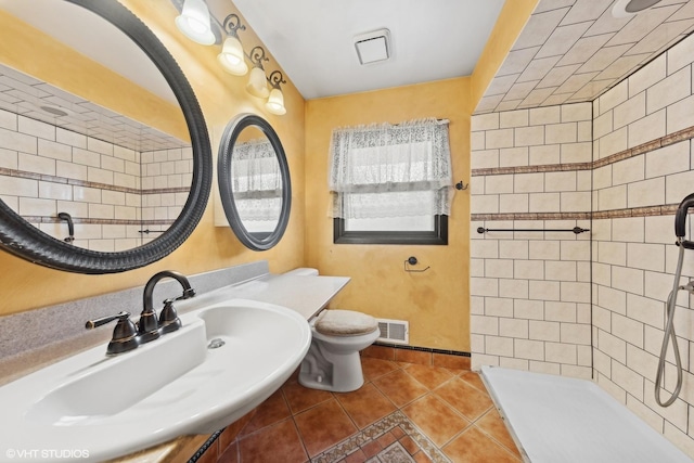 bathroom with toilet, a tile shower, tile patterned floors, and sink