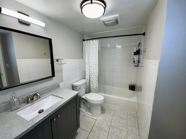 full bathroom with vanity, shower / bath combination with curtain, tile patterned flooring, toilet, and tile walls