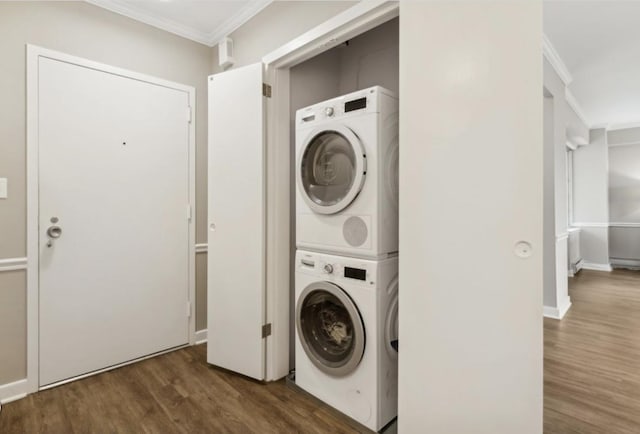 washroom with dark wood-type flooring, stacked washer / drying machine, and crown molding