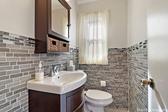 bathroom featuring vanity, tile walls, and toilet