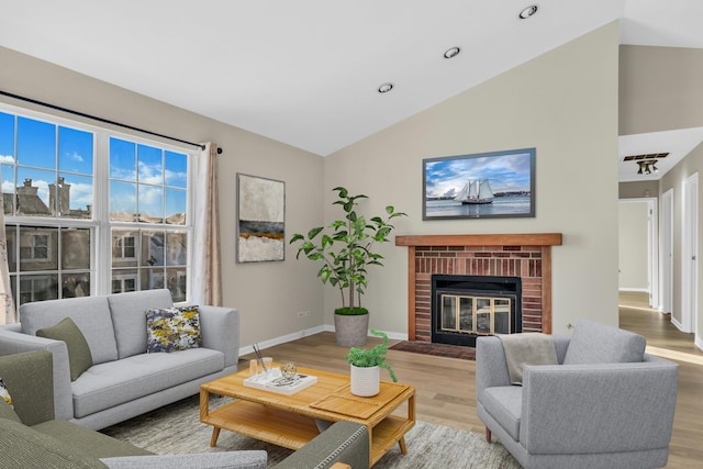 living room with lofted ceiling, a brick fireplace, and light hardwood / wood-style floors