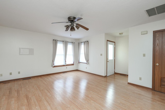 empty room with ceiling fan, light wood-type flooring, and a textured ceiling