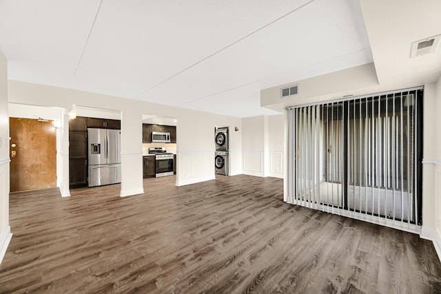 unfurnished living room with dark hardwood / wood-style flooring and stacked washing maching and dryer