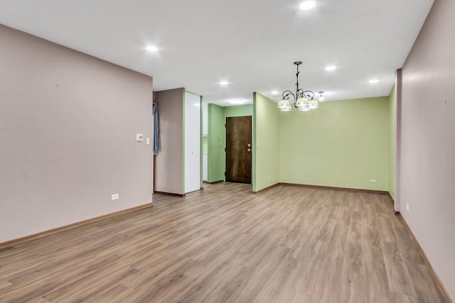 empty room with light hardwood / wood-style flooring and a chandelier