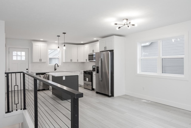 kitchen featuring pendant lighting, white cabinets, stainless steel appliances, and an inviting chandelier