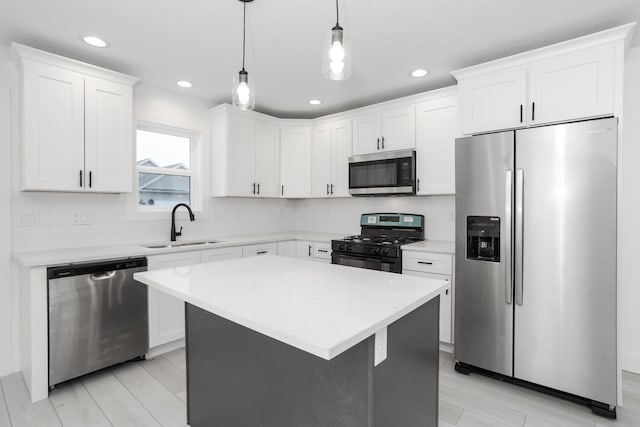 kitchen featuring a center island, hanging light fixtures, sink, appliances with stainless steel finishes, and white cabinetry