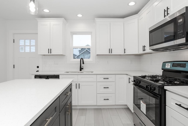 kitchen with decorative backsplash, appliances with stainless steel finishes, white cabinetry, and sink