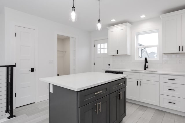 kitchen with a center island, sink, hanging light fixtures, decorative backsplash, and white cabinets