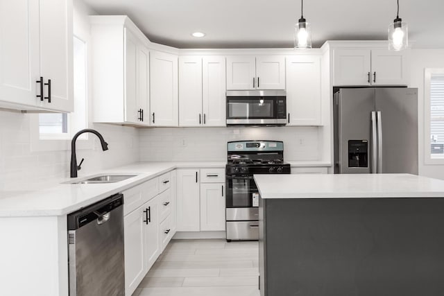 kitchen with pendant lighting, sink, white cabinetry, and stainless steel appliances