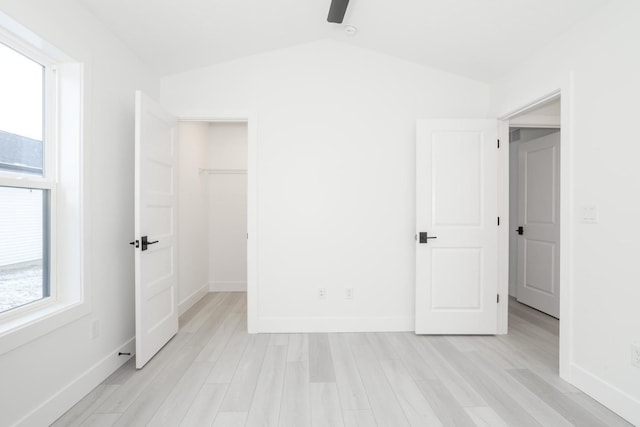 unfurnished bedroom with light hardwood / wood-style floors, vaulted ceiling, and multiple windows