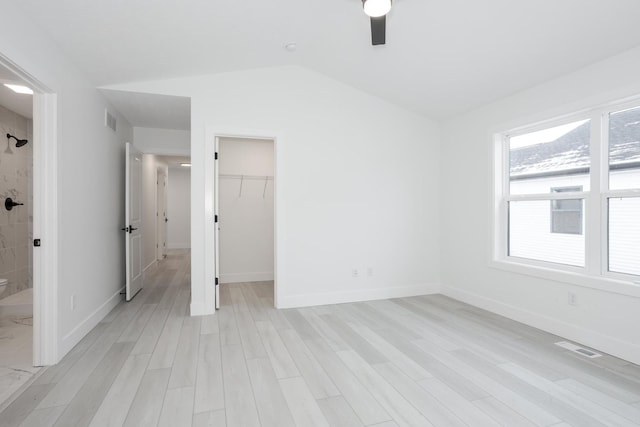 unfurnished bedroom with ceiling fan, a spacious closet, light hardwood / wood-style flooring, a closet, and lofted ceiling