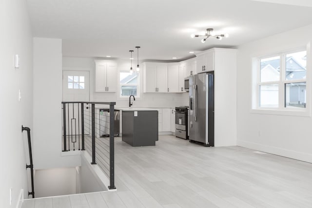 kitchen with a wealth of natural light, a center island, decorative light fixtures, and stainless steel appliances