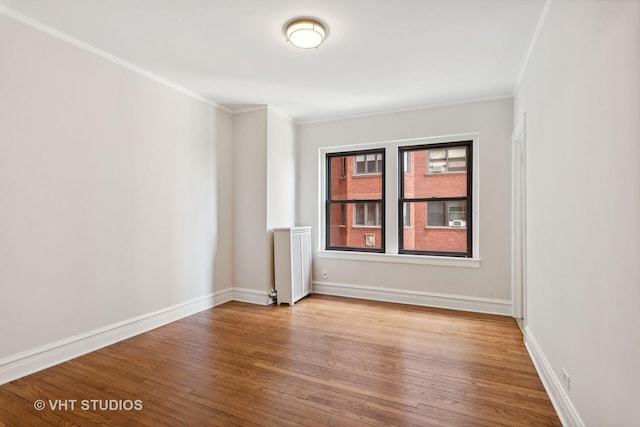 unfurnished room featuring hardwood / wood-style floors, ornamental molding, and radiator