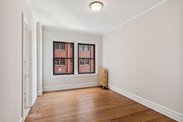 spare room with light wood-type flooring, crown molding, and radiator