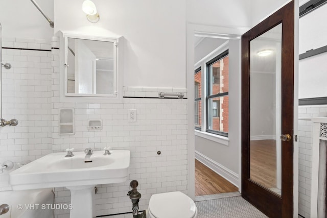 bathroom with hardwood / wood-style floors, toilet, and tile walls