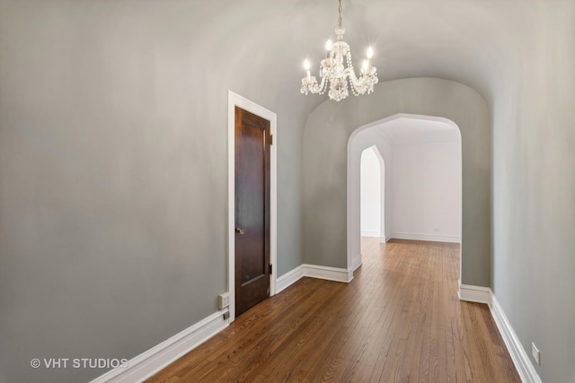 unfurnished dining area featuring wood-type flooring and a notable chandelier