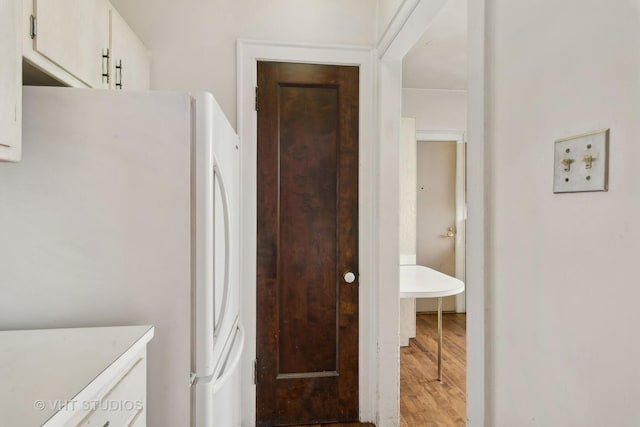 kitchen with white cabinets, light hardwood / wood-style flooring, and white fridge