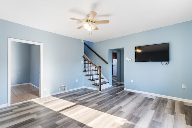 empty room with baseboards, visible vents, stairway, and wood finished floors