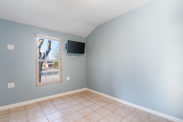 empty room featuring lofted ceiling, baseboards, and light tile patterned floors