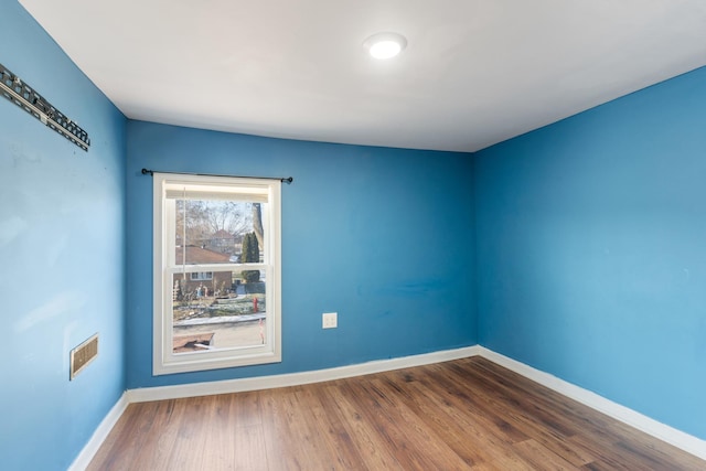 spare room with visible vents, baseboards, and wood finished floors