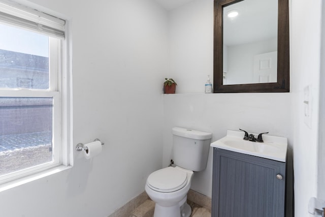 half bath featuring vanity, toilet, and baseboards