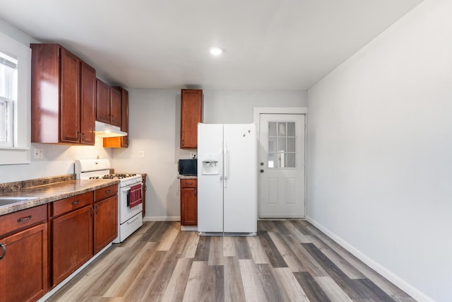 kitchen with light wood-style flooring, white appliances, under cabinet range hood, and baseboards