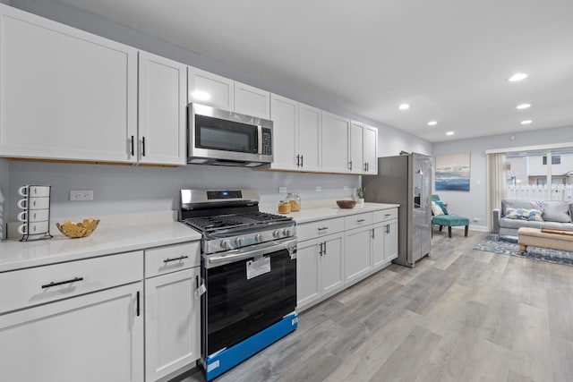 kitchen with white cabinets, stainless steel appliances, and light hardwood / wood-style flooring