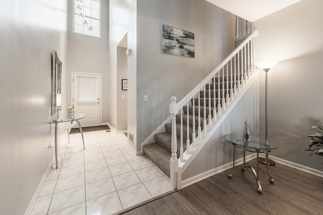 stairway with hardwood / wood-style flooring and a towering ceiling