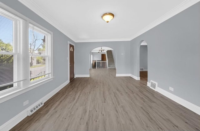 unfurnished living room featuring crown molding, wood-type flooring, and a notable chandelier