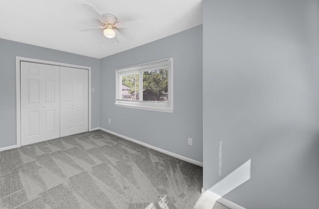 unfurnished bedroom with ceiling fan, light colored carpet, and a closet