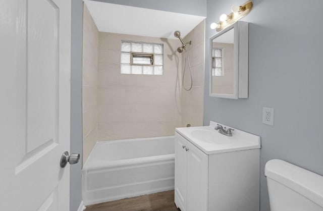 full bathroom with vanity, tiled shower / bath combo, hardwood / wood-style flooring, and toilet