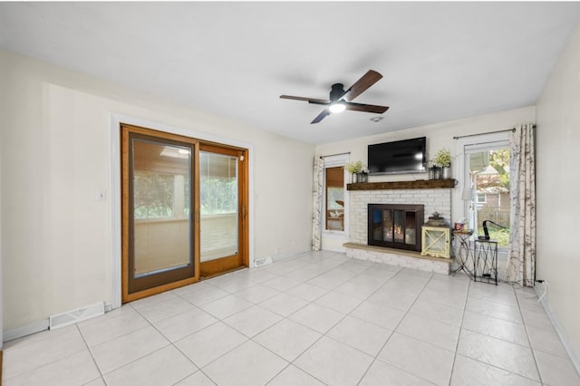 unfurnished living room featuring ceiling fan, light tile patterned flooring, and a brick fireplace