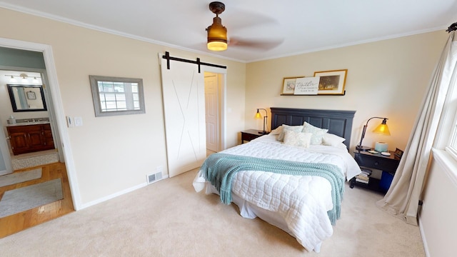 bedroom with light carpet, ensuite bathroom, ceiling fan, crown molding, and a barn door