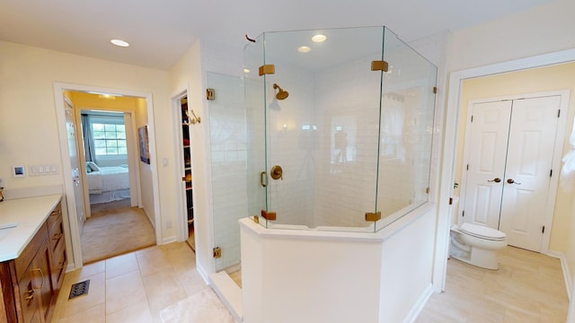 bathroom with tile patterned flooring, toilet, an enclosed shower, and vanity