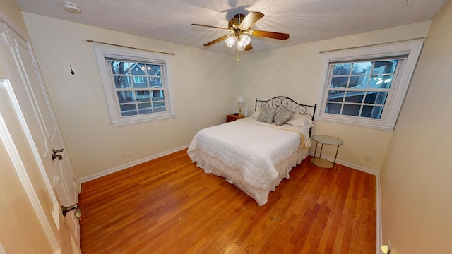 bedroom with ceiling fan, wood-type flooring, and multiple windows