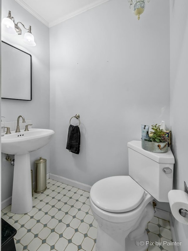 bathroom with toilet, ornamental molding, and sink