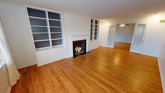 unfurnished living room with french doors, light hardwood / wood-style flooring, and crown molding