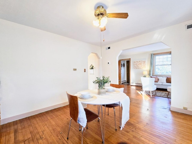 dining room featuring wood-type flooring, ceiling fan, and a baseboard heating unit