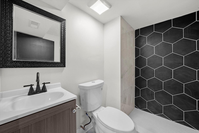 bathroom with vanity, toilet, and tiled shower