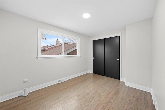 unfurnished bedroom with light wood-type flooring and a closet