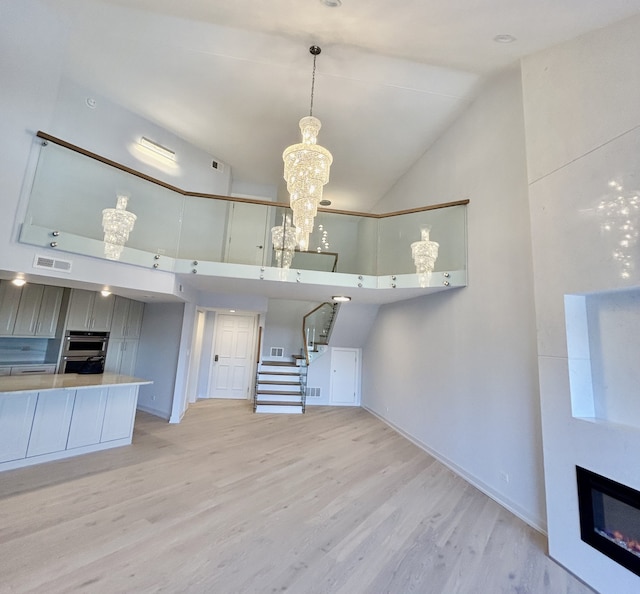 kitchen with a chandelier, light wood-type flooring, and high vaulted ceiling