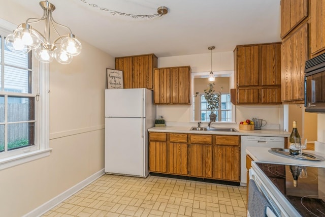 kitchen with sink, decorative light fixtures, white appliances, and an inviting chandelier