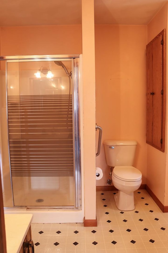 bathroom featuring tile patterned floors, vanity, a shower with shower door, and toilet