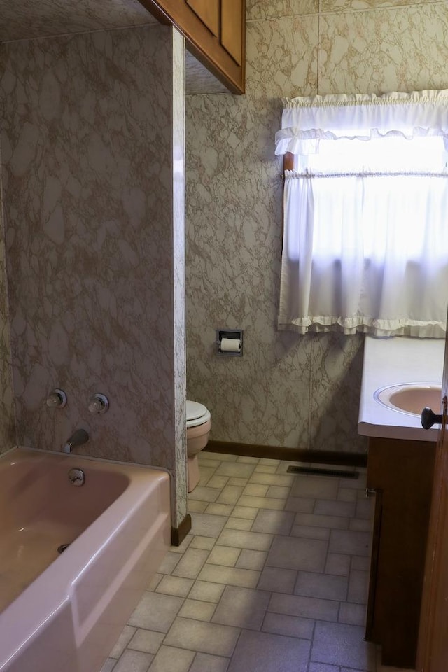 bathroom featuring vanity, toilet, and a tub