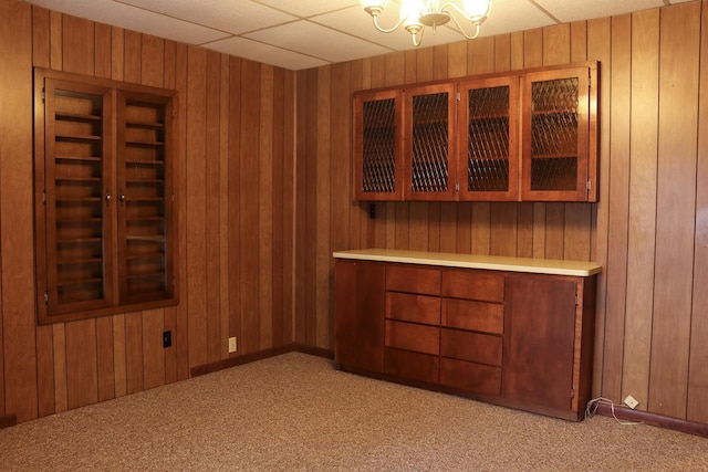 carpeted spare room with wooden walls and a drop ceiling