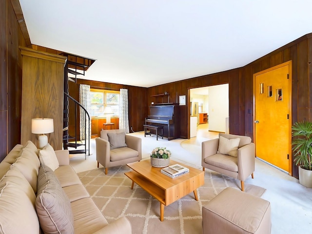 living area featuring wooden walls, stairway, and light colored carpet