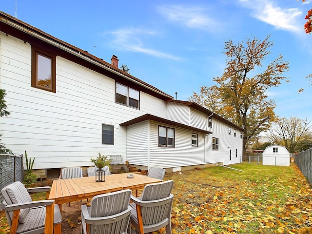 rear view of house featuring a yard, outdoor dining area, a chimney, and a fenced backyard