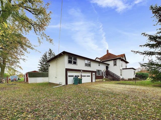 rear view of property with driveway, an attached garage, and a lawn