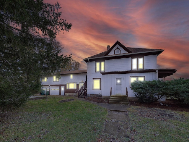 back of property at dusk with a yard and a chimney